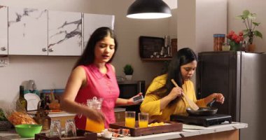 İnternetten yemek tarifi izlerken iki kadın yemek yapıyor.