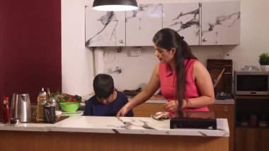 Anne ve oğul birlikte mutfağı temizliyor.