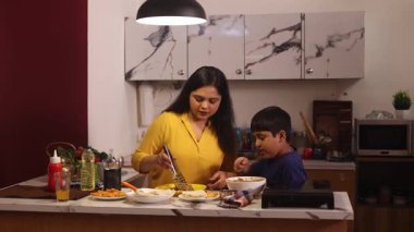 Kadın oğluna yemek servisi yapıyor.