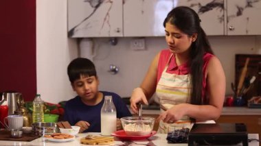 Oğlum sütü hamurun içine dolduruyor ve anne karıştırıyor.