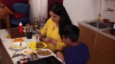 Annesi oğluna kahvaltı servisi yapıyor.