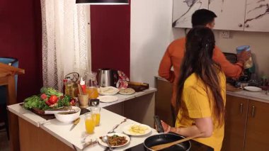 Karı koca mutfakta birlikte yemek pişirirken abur cubur yiyorlar.