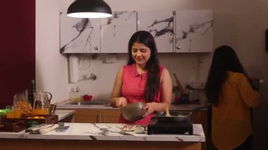 İki kadın birlikte kek pişiriyor ve selfie çekiyor.