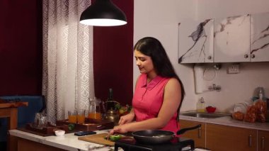 Müziğin tadını çıkarırken yemek yapan bir kadın.