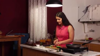 Sebze doğrayan ve yemek yapan bir kadın.