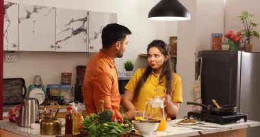 Karı koca mutfakta birbirine meyve suyu veriyor.