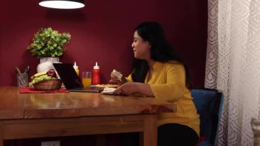 Bir kadın kahvaltı yapıyor ve video görüşmesinde konuşuyor.