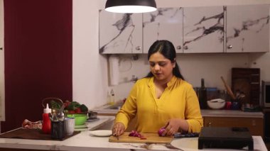 Soğan doğrayan bir kadın ve kocası ona mutfakta yardım etmeye gelmiş.