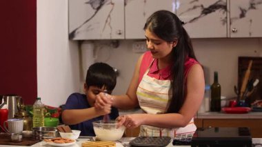 Oğlum çırpıcıyla hamuru karıştırıyor ve annesi yardım ediyor.