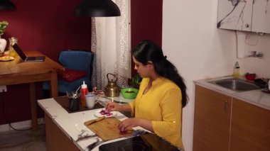 Soğan doğrayan bir kadın ve kocası ona mutfakta yardım etmeye gelmiş.