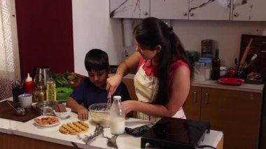 Oğlum çırpıcıyla hamuru karıştırıyor ve annesi yardım ediyor.