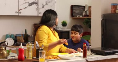 Annesi oğluna kahvaltı servisi yapıyor.