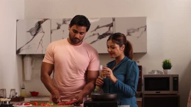 Kadın adama meyve suyu verirken, adam havuç kesiyor.