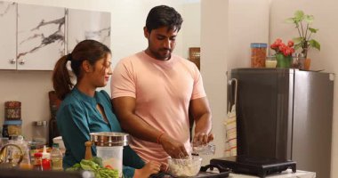 Çift mutfakta birlikte yemek pişiriyor.