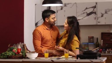 Karı koca meyve suyunu paylaşıyor ve mutfakta romantik bir anın tadını çıkarıyorlar.