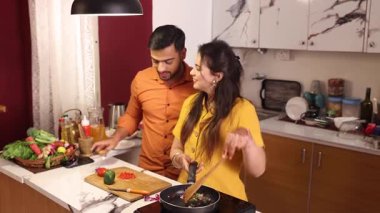 Karı koca mutfakta birlikte yemek pişiriyorlar.