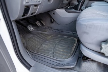 Dirty car floor mats of black rubber under passenger seat in the workshop for the detailing vehicle before dry cleaning. Auto service industry. Interior of sedan. clipart