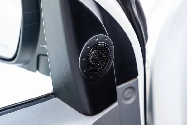 Modern round speaker grille in black color on the door inside the car interior, circle dynamics with chrome elements in the design on the gray panel. Auto service industry. Loud music concept.