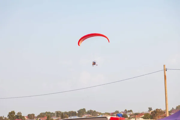 在温暖的夏日 一辆红色机动滑翔机载着两名乘客在蓝天中飞行 飞行运动 — 图库照片