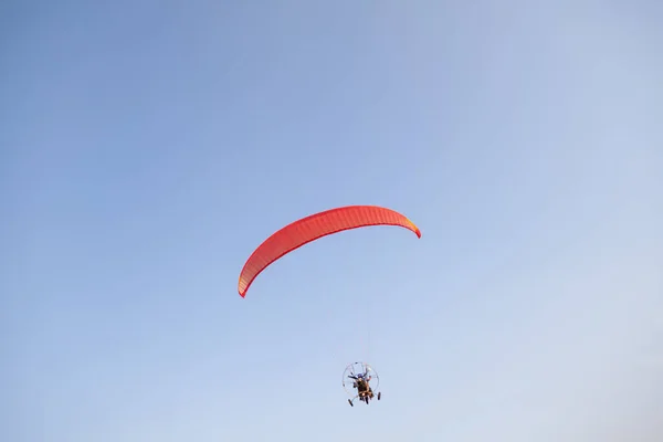 在温暖的夏日 一辆红色机动滑翔机载着两名乘客在蓝天中飞行 飞行运动 — 图库照片