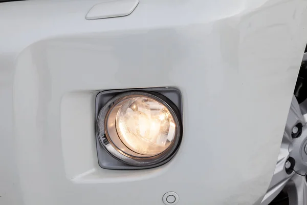 Front bumper fog lamp view of silver car after cleaning before sale in a workshop for repair and detailing vehicles auto service industry. Road safety while driving. Transportation lighting.
