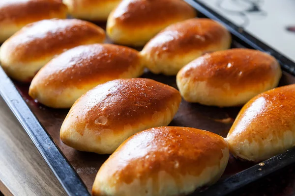 stock image Russian meat piroshki. Traditional hand mini pies on wooden background. Rustic style, closeup view. Russian traditional patties usually made by grandmothers.