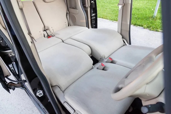 Close-up on front and rear seats with velours fabric upholstery in the interior of an Japan  kei car in beige after dry cleaning folded in to big space for sleeping like sofa.