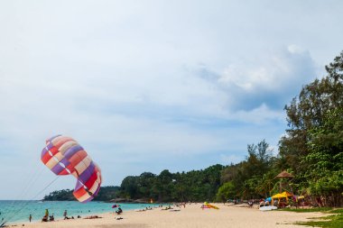 Tayland, choeng thale - 03.28.23 Choeng Thale şehrindeki güzel Surin plajı, Phuket, Tayland renkli paraşüt beyaz kum, turkuaz su ve palmiye ağaçları