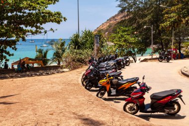 Tayland, Nai Harn plajı - 03.30.23: Tayland 'da Phuket Adası' ndaki güzel parlak nai harn plajı açık turkuaz su, beyaz kum, mavi gökyüzü ve kiralık motosikletler. 