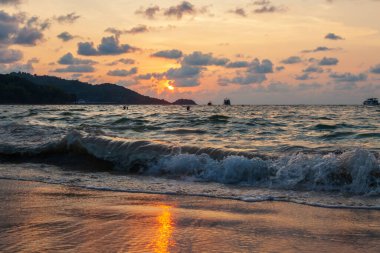 Okyanustaki dalgaların manzarası ve altın saatinde bronz güneşin Tayland 'da gün batımında Phuket adasında, patong plajında görüldüğü inanılmaz bir manzara.