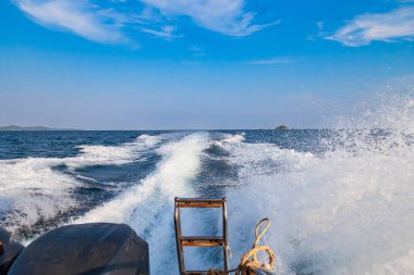 Mavi denizdeki sürat teknesinden gelen dalgalar, su sıçramaları ve bir tekne ya da yatın izleri. Sıcak Asya ülkelerinde tatildeyken seyahat ve seyahat kavramı.