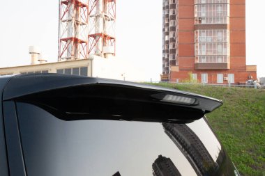 Yarış sırasında arabanın aerodinamiklerini geliştirmek için arka camında plastik spoyler bulunan siyah bir arabanın kapağına yakın plan..