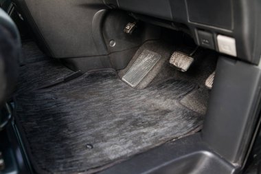 Kuru temizlemeden sonra temizlik aracının atölyesinde gaz pedalları ve frenleri olan siyah halı paspasları.