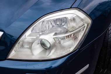 Satıştan önce çamaşır makinesiyle temizledikten sonra mavi renkli arabanın ön far görüntüsü. Öncü drl ve xenon mercekli araçta büyük lamba.