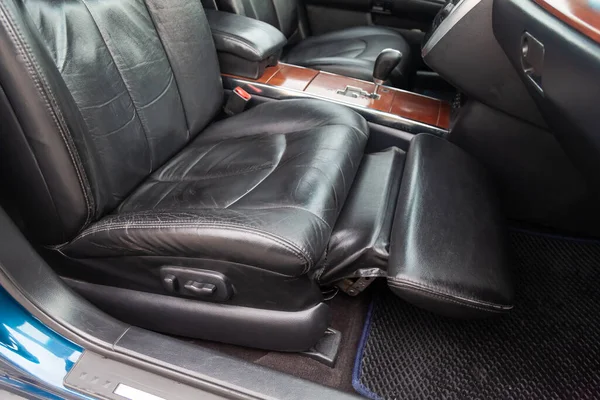 Close-up on front passenger seat with black leather trim and ottoman for legs rest upholstery in the interior of an Japanese car in gray after dry cleaning. Auto service industry.