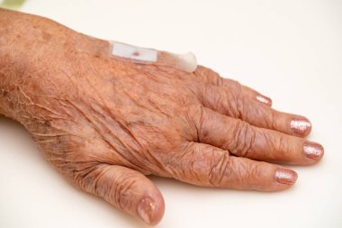 Yaşlı kadının elini, üst uzvunu ya da kolunu yaralılara kapatın, beyaz arka planda kanlı ve tuzlu bir hasta giydirme yarasına hemşire tedavisi için bekliyorlar..