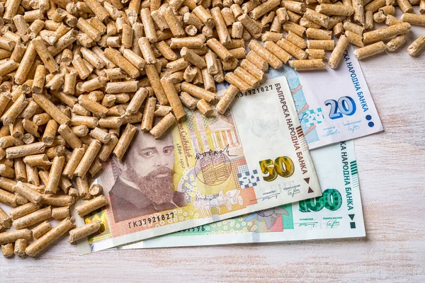 Wood pellets heap and bulgarian lev banknotes close-up. Bio fuel costs, buy and sell pellets. Organic biofuel from compressed sawdust prices. Ecological heating, alternative energy concepts. Top view.