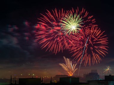 Gece yarısı gökyüzünde şenlikli havai fişekler patladı. Kırmızı beyaz havai fişekler geleneksel bayram etkinliğini kutlayan beyaz şehirde patladı. Piroteknik ve havai fişek konsepti. Uzun bir gece sahnesi. Açık havada..