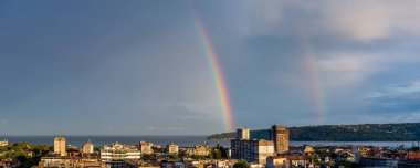 Yaz akşamında deniz kenarı kasabasında çifte gökkuşağı. Varna Bulgaristan 'ın ufuk çizgisinde muhteşem bir gökkuşağı. Yoğunluk manzarası, gökyüzü ve deniz üstüne yağmur. Panorama. Hava Durumu. 