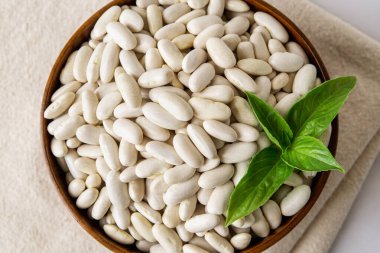 Tahta bir kasede beyaz fasulye manzarası. Beyaz böbrek fasulyesi, kuru fasulye, fırında pişmiş fasulye vejetaryen yemekleri için haricot. Bitki proteini, hasat, organik ürün konsepti. Yakın plan..