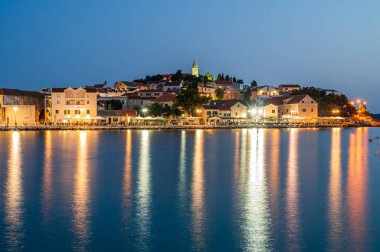Şafakta Sibenik yakınlarında Hırvatistan kıyısında antik bir balıkçı köyü olan Primosten 'in eski bir kasabasının manzarası