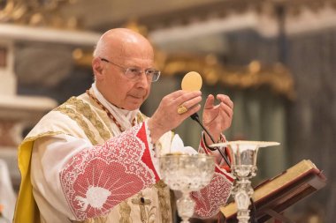 GENOA, ITALY - APRIL 22 2023: Archbishop Angelo Bagnasco during the Mass in the Communion Rite in Assunta Church in Sestri Ponente clipart