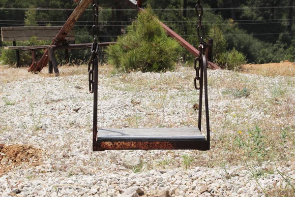 Terk edilmiş bir oyun parkında demir ve ahşaptan yapılmış salıncak. Salıncak