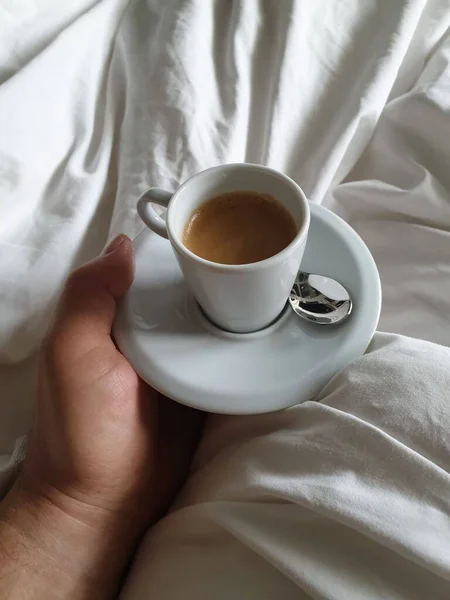 Drinking espresso coffee in bed at a hotel