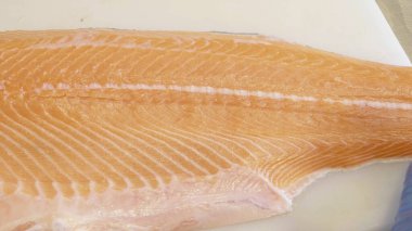 Cutting fresh raw Norwegian salmon fish in store