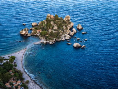 Sicilya, Taormina yakınlarındaki küçük bir ada olan Isola Bella 'nın nefes kesici hava manzarası gün batımının sıcacık parıltısıyla yıkandı. Turkuaz sular adanın yemyeşil sularıyla ve tepesindeki tarihi binalarla çok güzel tezat oluşturuyor.