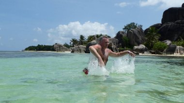 A man in a jump in a splash of water in the Seychelles
