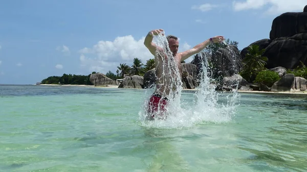 A man in a jump in a splash of water in the Seychelles