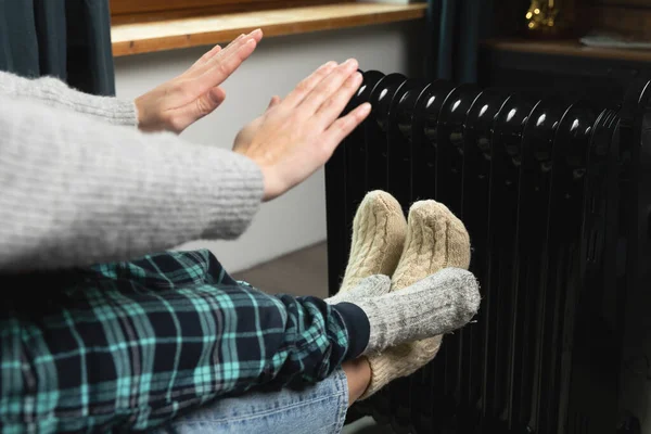 妇女和儿童坐着取暖 手牵着手和电热器 高企的能源价格和冷酷的家 免版税图库图片