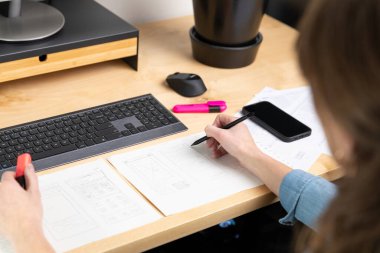 Sketch of wireframe for website. Women designer working on a mobile application, drawing on paper.